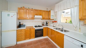Une cuisine avec des meubles de rangement en bois, un réfrigérateur blanc, une cuisinière et un lave-vaisselle.