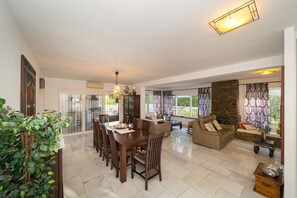 A spacious living area with a dining table, sofas, and a fireplace. - Villa Santana with Mountain Views, Private Pool, Terraces, and Wi-Fi (Alfaz del Pi)