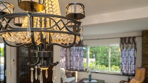 Un lampadario con decorazioni in cristallo, un divano, un tavolino da caffè e una finestra con tende.