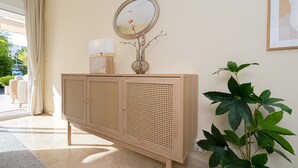 Une console en bois, un miroir, un vase avec des fleurs et une plante en pot.