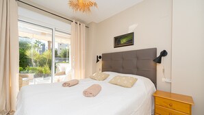 Une chambre à coucher avec un lit, une table de chevet, une fenêtre avec des rideaux et une vue sur la verdure.