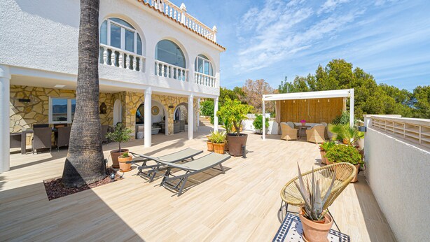 Une vaste terrasse extérieure dotée d’une piscine, de chaises longues et de plantes en pot.
