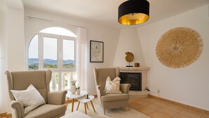 Un salon comprenant deux fauteuils, une petite table, une cheminée et un grand élément décoratif circulaire fixé au mur.