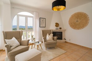 A living room with two armchairs, a small table, a fireplace, and a large circular wall decoration.