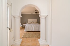 A bedroom with a bed, a ceiling fan, and a nightstand with lamps.