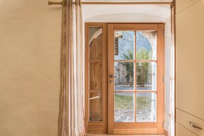 Une porte en bois avec des panneaux de verre, une poignée en métal et une vue sur l’extérieur.