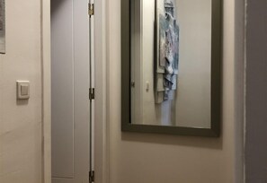 Une pièce dotée d’une porte coulissante, d’un interrupteur et d’un miroir dans lequel se reflète un vêtement suspendu.