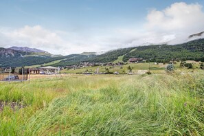 A rural village with houses, a parking area, and a mountain backdrop.