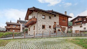 Un edificio a più piani con mura in pietra, balconi in legno e un cortile in pietra.