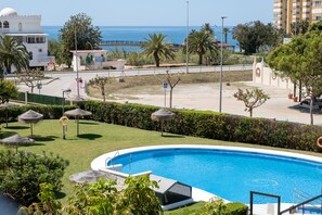 Zona de piscina con vista despejada al mar, un edificio blanco con cúpula y una palmera.