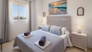 Ein Hotelzimmer mit einem Bett, zwei Nachttischen, einem Fenster und einem Bild an der Wand.