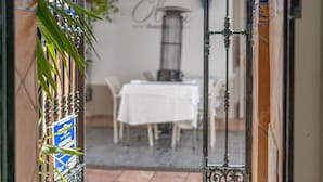 An open doorway leading to a dining area with a white tablecloth-covered table and chairs, a potted plant, and a wall with a sign. - Las Brisas Estepona (Estepona)
