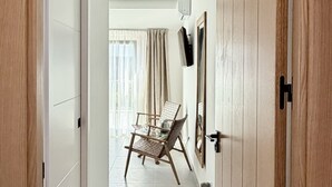 A hallway with a wooden door, a chair, and a television on the wall. - Las Brisas Estepona (Estepona)