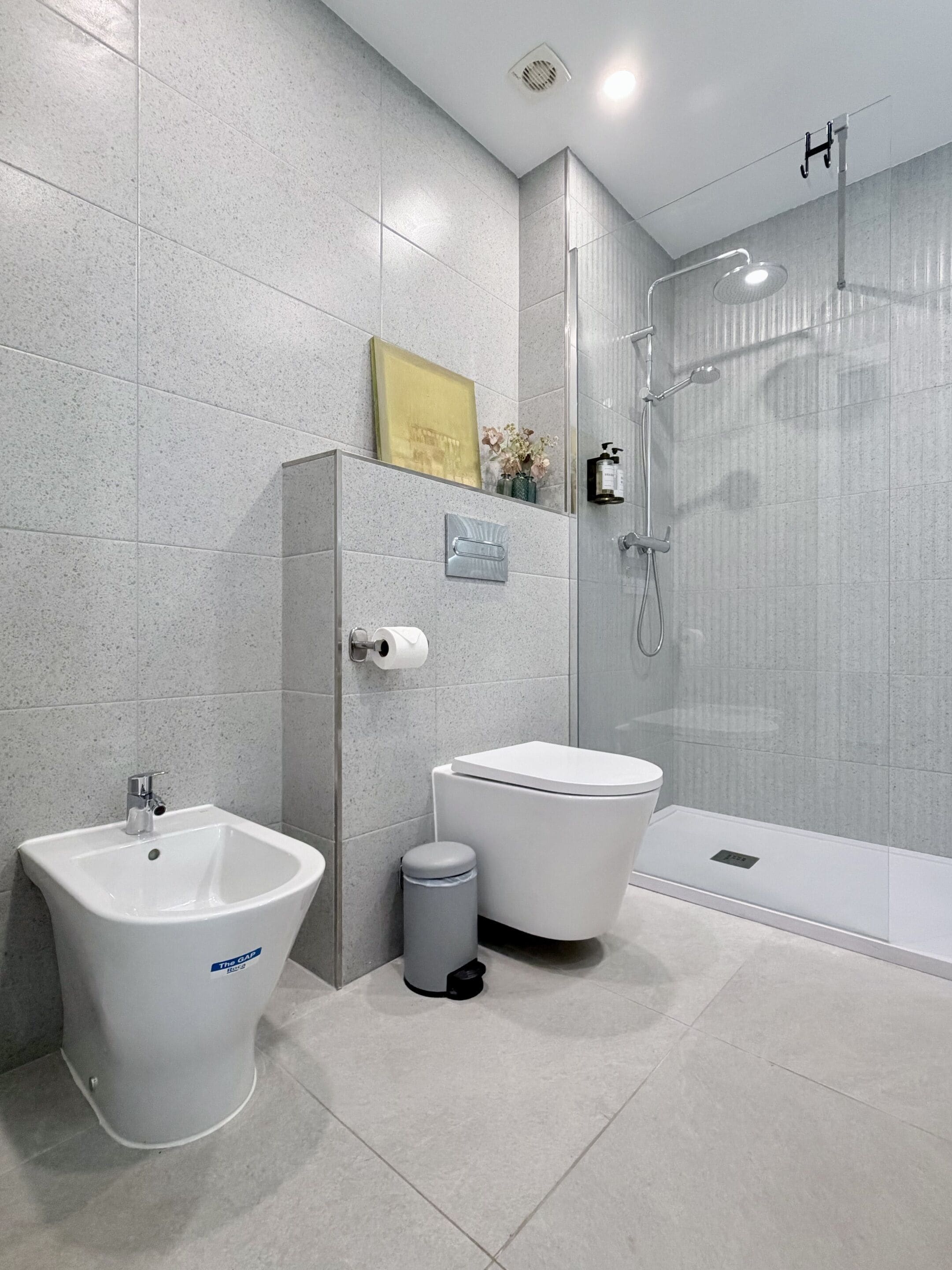Ein modernes Badezimmer mit einem Bidet, einer Toilette und einer in Glaswänden gefassten Dusche.