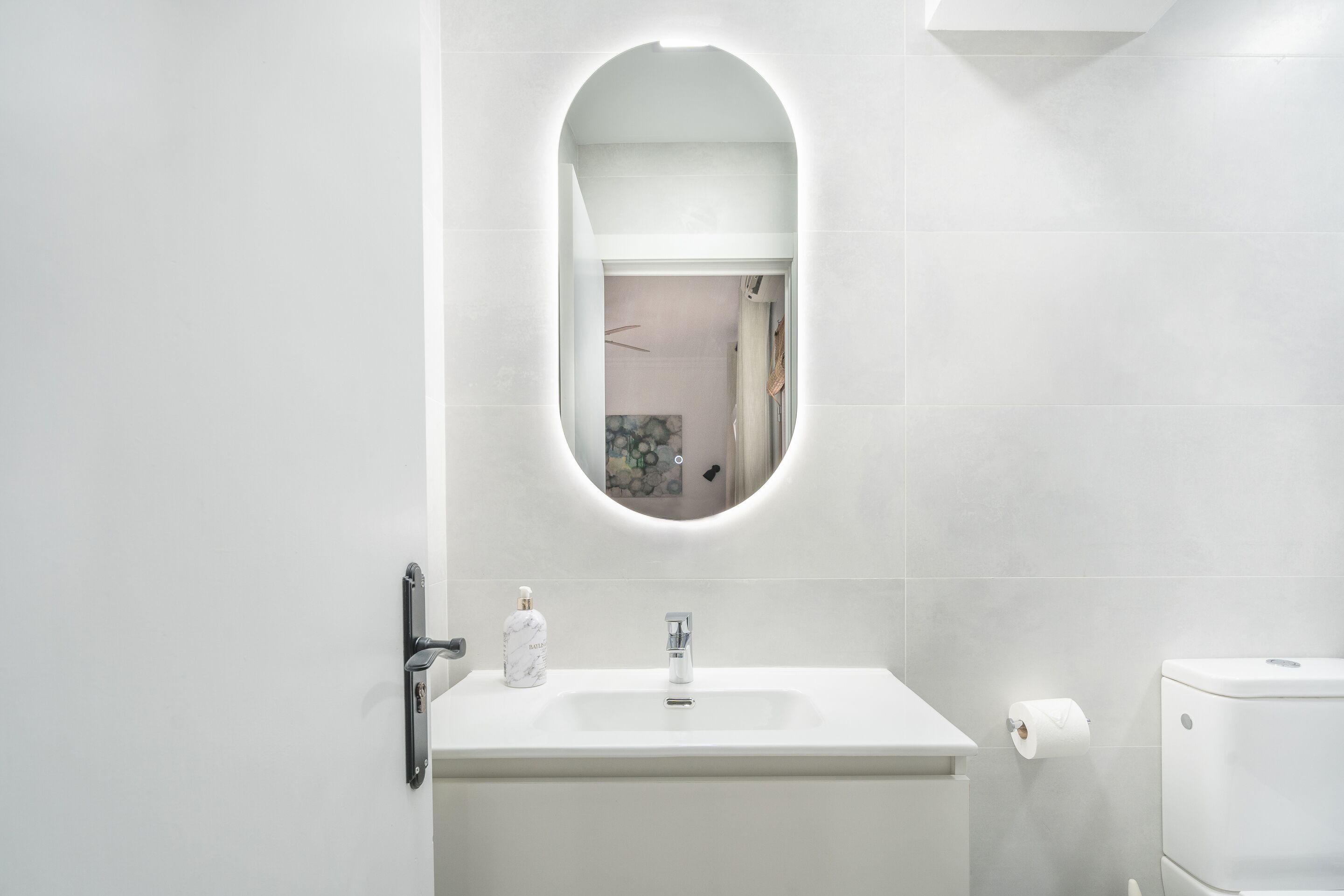 Un bagno moderno con un lavandino bianco, uno specchio e un water.