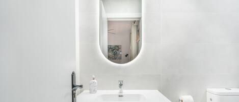 Un bagno moderno con un lavandino bianco, uno specchio e un water.