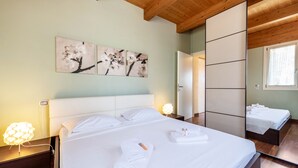 A hotel room with a large bed, a bedside table with a lamp, and a mirror. - Apartment 'Rocchetta' with Lake View, Wi-Fi and Air Conditioning (Salò)