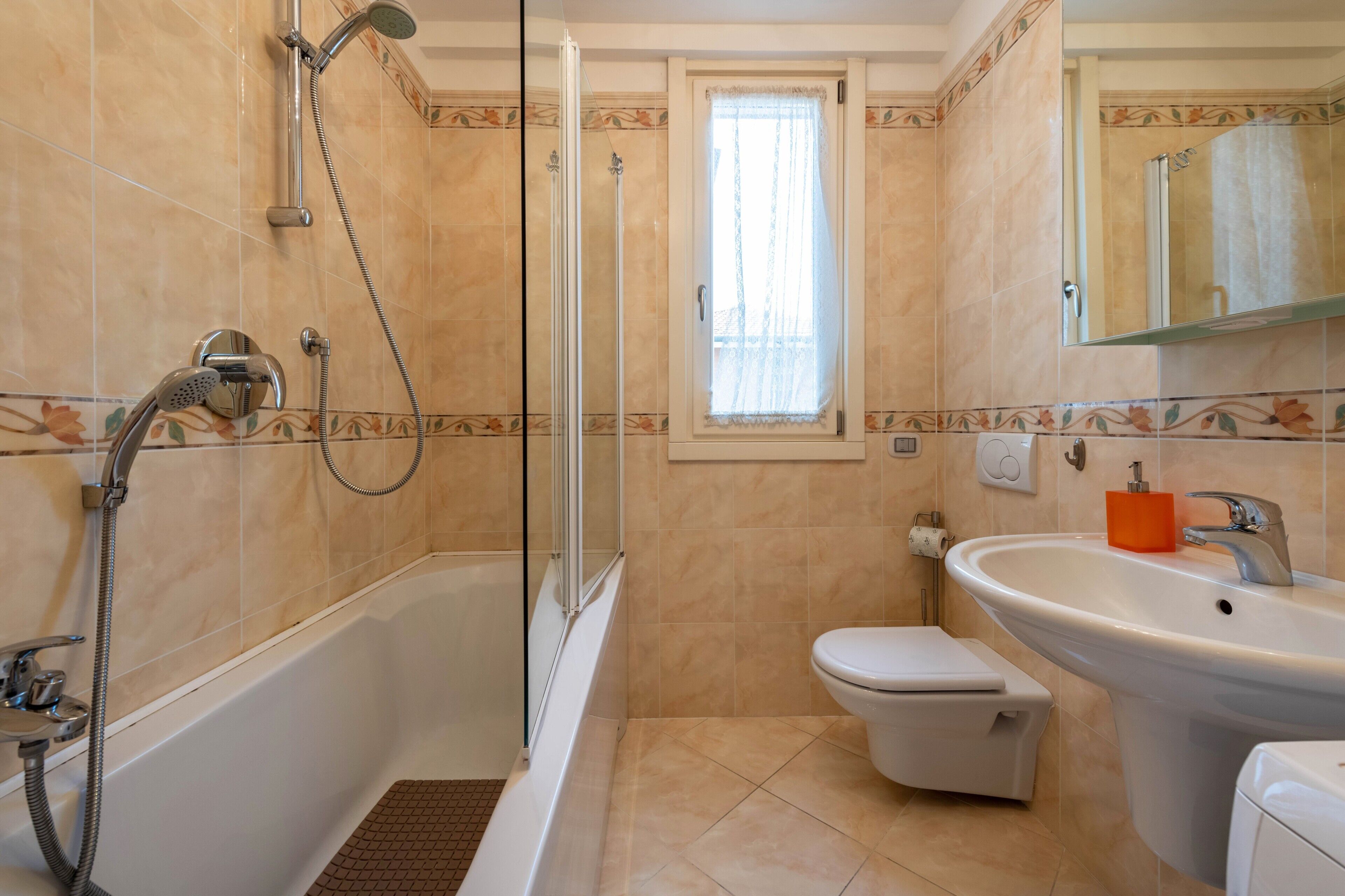 Un baño con bañera, ducha, inodoro, lavabo y ventana con cortina.