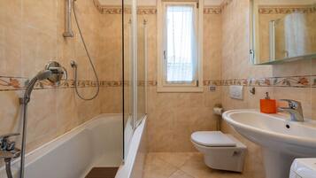 Un baño con bañera, ducha, inodoro, lavabo y ventana con cortina.