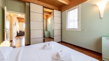 Quarto de hotel com uma cama, guarda-roupa, janela e porta que dá para outro quarto.