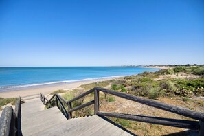 A wooden staircase leading to a beach with a clear view of the ocean. - Apartment Punta Candor close to the Beach with Pool, Terrace & Wi-Fi (Rota)
