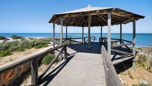 Un quiosco de madera con techo y piso de madera, con vista al océano.