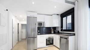 Una cocina moderna con armarios blancos, un refrigerador de acero inoxidable, un microondas y un horno.