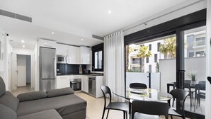 Un apartamento moderno con sala de estar, cocina y balcón con vistas a edificios.