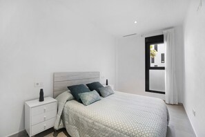 Une chambre à coucher avec un lit, une table de chevet et une fenêtre avec des rideaux.