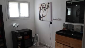 Un bagno con un mobile lavabo nero, uno specchio, un quadro appeso e una finestra.