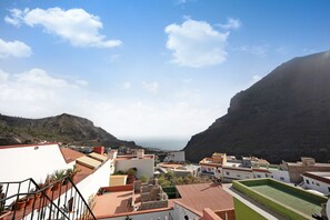 A coastal town with buildings, a mountain, and a clear sky.