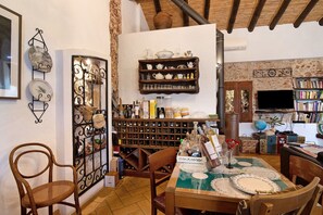Um quarto acolhedor com uma mesa de madeira, cadeiras, um suporte para vinhos e uma estante de livros.