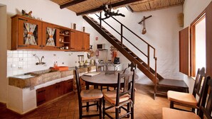 A kitchen with wooden cabinets, a herringbone floor, a dining table with chairs, and a staircase.