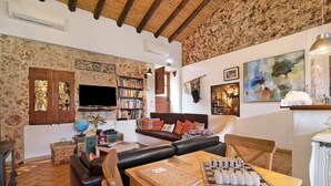 A cozy living room with a fireplace, a television, a bookshelf, a sofa, and a dining table with a chessboard.