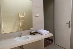 A bathroom with a sink, mirror, towel rack, and a door. - Vogelkopf Resort (Waisai)