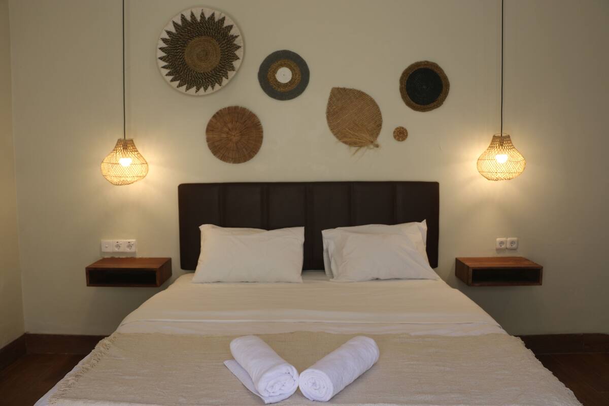 A neatly made bed with white linens, two bedside tables with lamps, and decorative wall art.