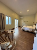 Una habitación amplia con una cama, una zona de estar con una mesa y un gran ventanal.