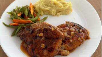 Une assiette comprenant un morceau de viande, de la purée de pommes de terre et un accompagnement de légumes variés.