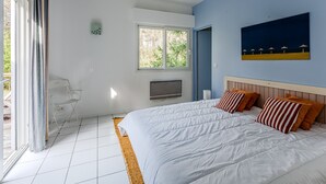 Une chambre avec un grand lit, une télévision, une fenêtre et une porte donnant sur un balcon.