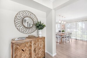 A modern interior with a herringbone wooden cabinet, a decorative mirror, and a dining area with white chairs and a table.