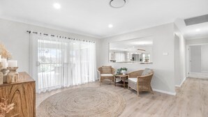 A modern living room with a round rug, wicker chairs, a wooden sideboard, and sheer curtains. - D'VINE COTTAGE - THE VINTAGE HOLIDAY HOUSES (Rothbury)