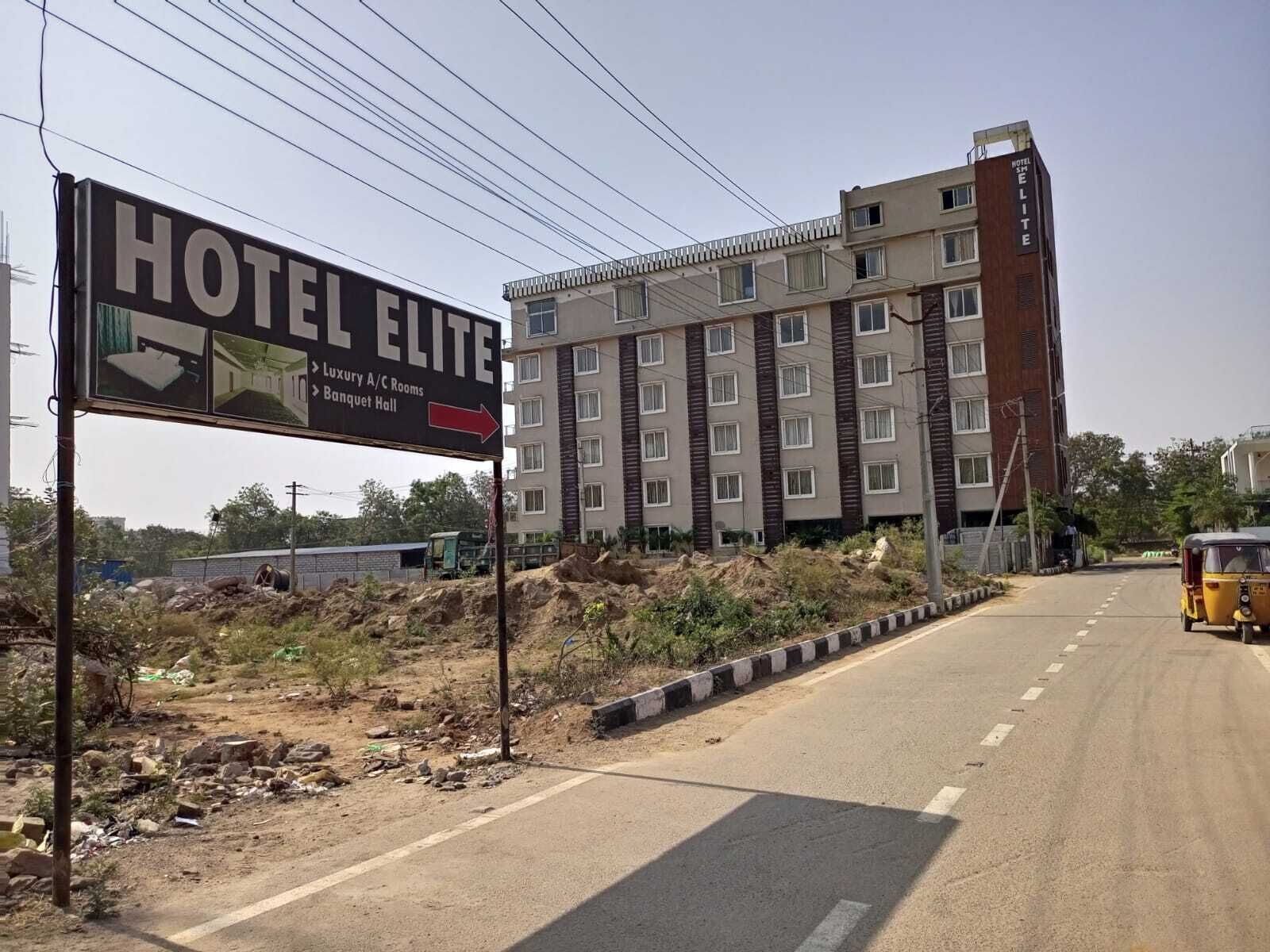 Ein mehrstöckiges Gebäude mit einem Schild, das anzeigt, dass es sich um ein Hotel namens "HOTEL ELITE" handelt, mit luxuriösen klimatisierten Zimmern und einem Bankettraum.