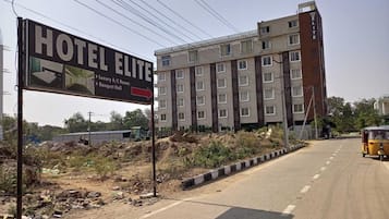 Ein mehrstöckiges Gebäude mit einem Schild, das anzeigt, dass es sich um ein Hotel namens "HOTEL ELITE" handelt, mit luxuriösen klimatisierten Zimmern und einem Bankettraum.