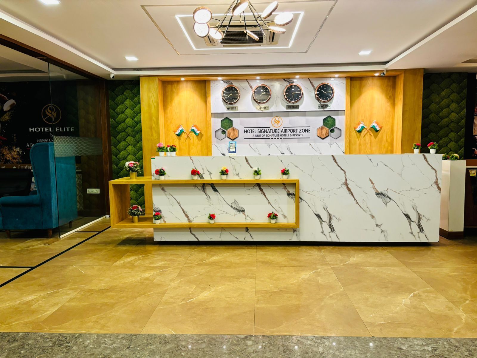 A hotel reception desk with a marble top, wooden accents, and a green textured wall behind.