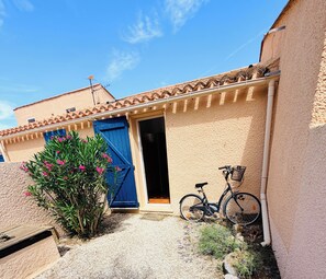 A building with a blue door, a bicycle, and a small garden area.