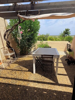 A patio area with a table and chairs, a hanging macrame light fixture, and a view of the landscape.