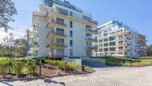 Ein mehrgeschossiges Wohnhaus mit Balkonen, einem gepflasterten Eingangsbereich und einem angelegten Garten.