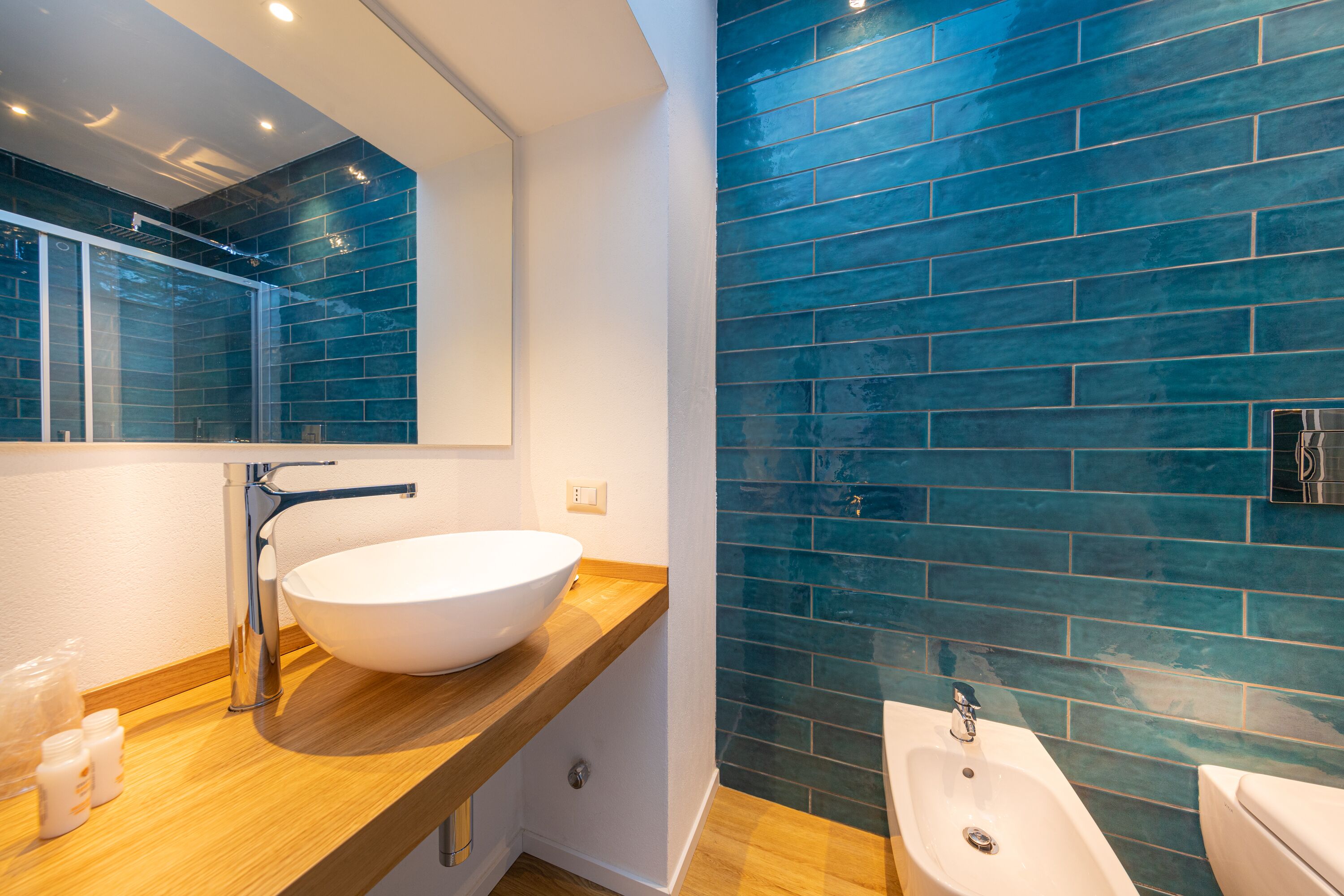 Un baño moderno con un espejo grande, un lavamanos blanco y un bidé.