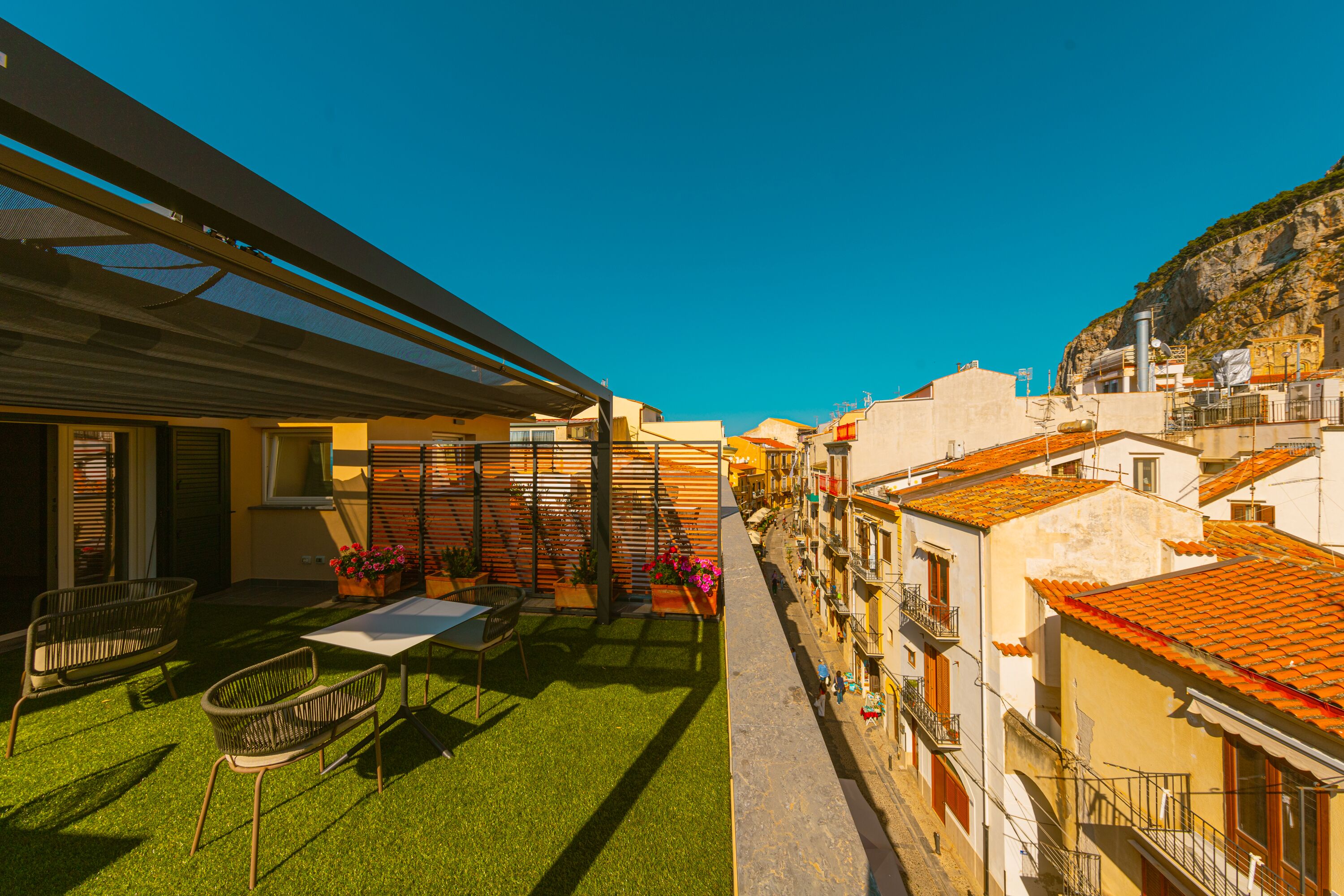 A courtyard with a table and chairs, a pergola, and a view of the street.
