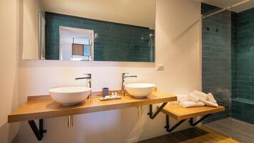 Un baño moderno con dos lavamanos grandes de color blanco, un mueble de tocador de madera, un espejo y una zona de ducha con azulejos azules.